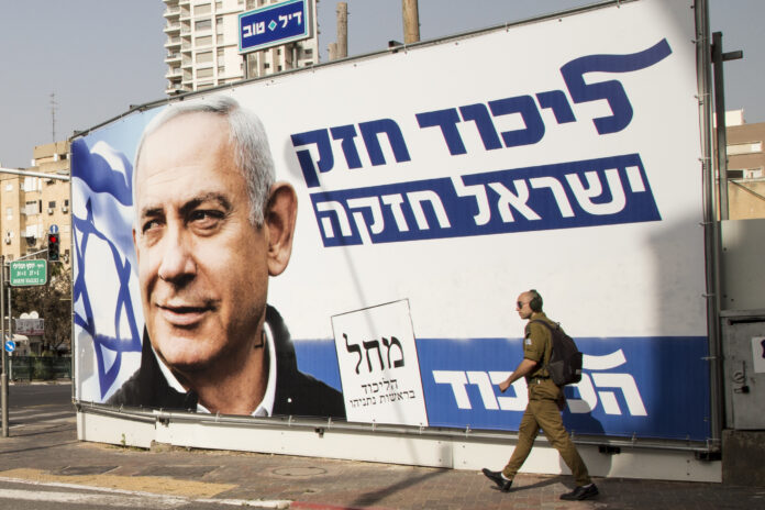 fotografia colori, esterno urbano diurno, grande manifesto elettorale di Benjamin Netanyahu con ritratto e scritte blu su sfondo bianco