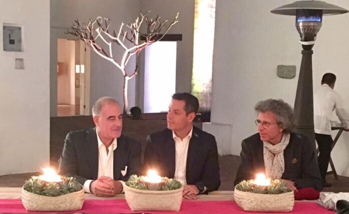 Fotografia colori, interno, 3 uomini seduti al tavolo con 3 centrotavola con candele accese, incontro formale presso ambasciata italiana in messico