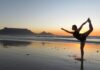 Fotografia colori, ragazza fa yoga in posizione signore della danza, in riva al mare al tramonto a Città del Capo Sudafrica