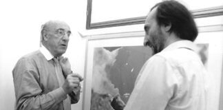 fotografia bianco nero biennale venezia 1997, interno, due uomini parlano davanti a quadro, a sinistra roger guillemin, a destra carmelo strano