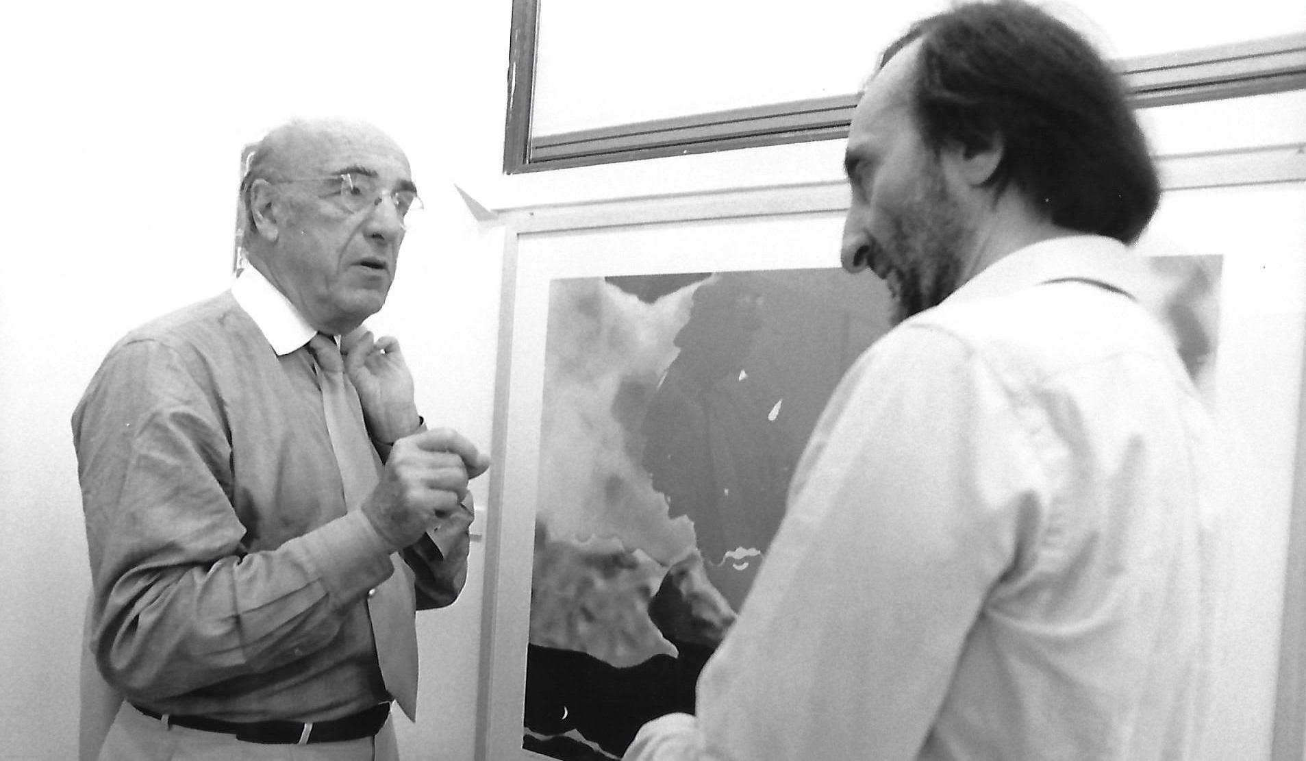 fotografia bianco nero biennale venezia 1997, interno, due uomini parlano davanti a quadro, a sinistra roger guillemin, a destra carmelo strano