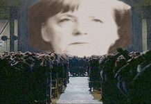 Angela Merkel versione "1984" di Gerge Orwell, la sua faccia è proiettata sullo schermo davanti ai suoi sudditi.