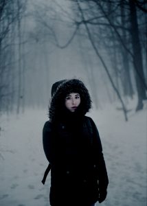 Ragazza con cappotto nero in paesaggio innevato