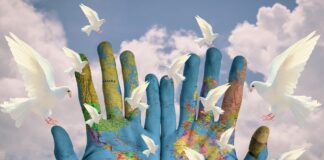 Carta geografica del mondo stampato su due mani aperte, e colombe bianche volanti, simbolo della pace mondiale