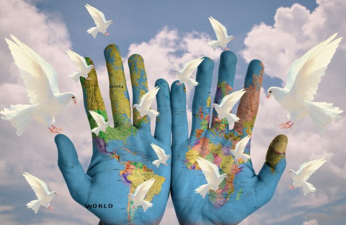 Carta geografica del mondo stampato su due mani aperte, e colombe bianche volanti, simbolo della pace mondiale