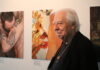 Edward Lucie-Smith standing. Behind him, in the background, two of his photographic works.