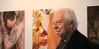 Edward Lucie-Smith standing. Behind him, in the background, two of his photographic works.