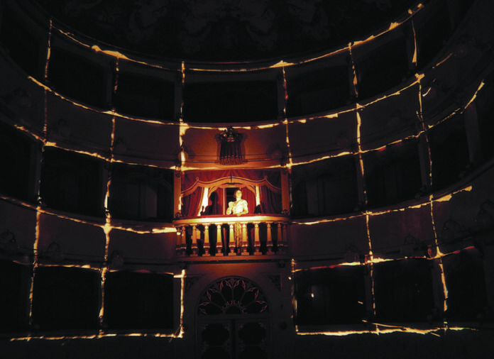 Scena al Teatro dei Coraggiosi, al centro l'attrice Giovanna Summo illuminata al centro su di una balconata