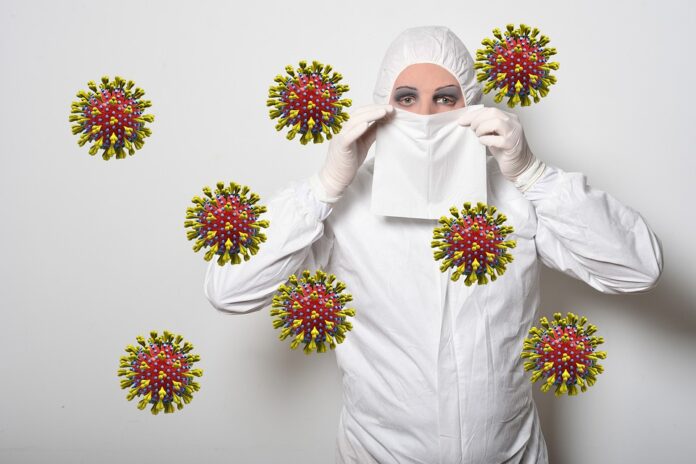 fotomontaggio, colori, riproduzioni ingigantite del coronavirus cinese viola e giallo, donna con tuta bianca anticontaminazione si tiene un fazzoletto bianco a coprire naso e bocca, sfondo bianco