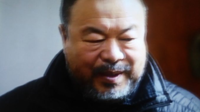 Foto sfocata di un uomo dai tratti orientali con lo sguardo basso e la bocca semi-aperta. L'uomo indossa una giacca blu