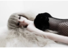 Bambola modello Barbie, sdraiata con capelli chiari e lunghi, fronte coperta da frangia, abito nero a rete.