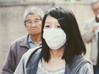 Image with an Asian girl wearing a white mask at to preserve herself from virus's attack.