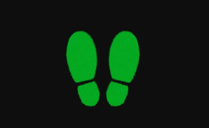 decoupling disaccoppiamento, concetto economico esemplificato da immagine di due impronte verdi di scarpe, sfondo nero