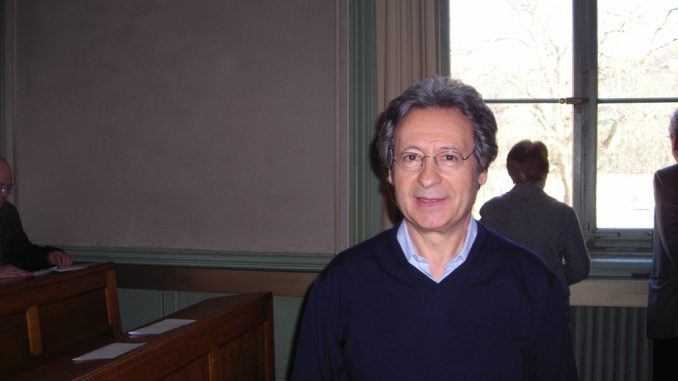 Angelo Gaccione scrittore fotografia, colori, interno, ritratto di Angelo Gaccione scrittore italiano e poeta, in aula presso università di Ginevra, uomo brizzolato, occhiali, maglione blu e camicia azzurra