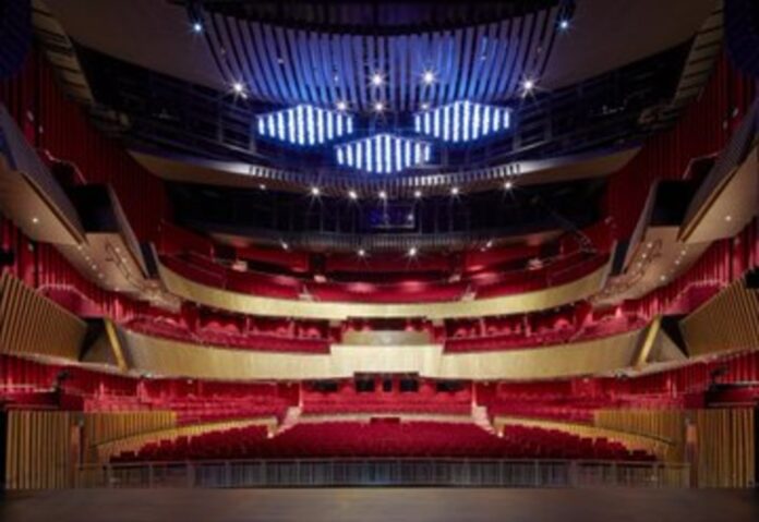 Interior of the Sheikh Jaber Al-Ahmed Cultural Center theater in Kuwait City, three-level hemicycle, with red armchairs and wooden structure.