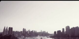 Black and white photograph of an ultramodern bridge and skyscrapers in the background, in the Chinese megalopolis Chongqing.