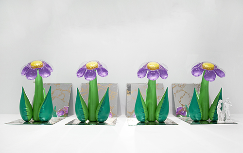 Il bello Quattro oggetti in plastica gonfiabile dalla forma di fiori con i petali viola sono disposti sopra quattro specchi