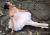 picture, exterior, colors, classical ballerina wearing a white tutu, sitting on black rocks, dance philosophy