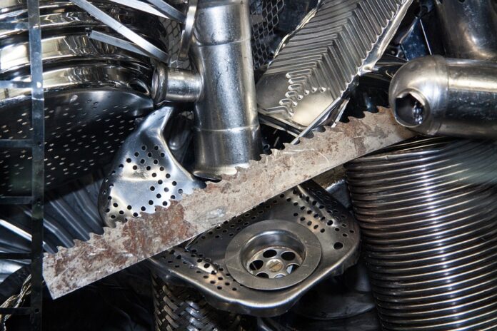 The photo shows several metal scraps, including a sawtoothed blade, a pipe, a pedal and a sink pipe union