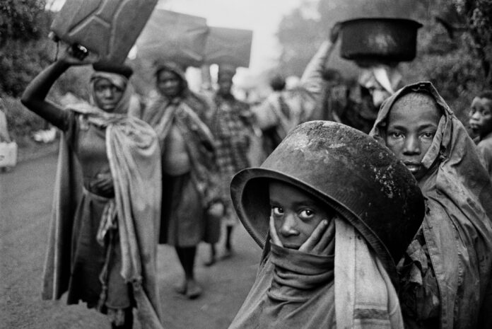 Sebastião Salgado Water supplies are often far away from the refugee camps. l'immagine in bianco e nero ritrae un gruppo di profughi dello Zaire, tra cui una bambina