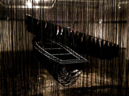 installation by the japanese artist Chiharu Shiota wirh two boats and many black ropes around them