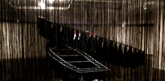 installation by the japanese artist Chiharu Shiota wirh two boats and many black ropes around them