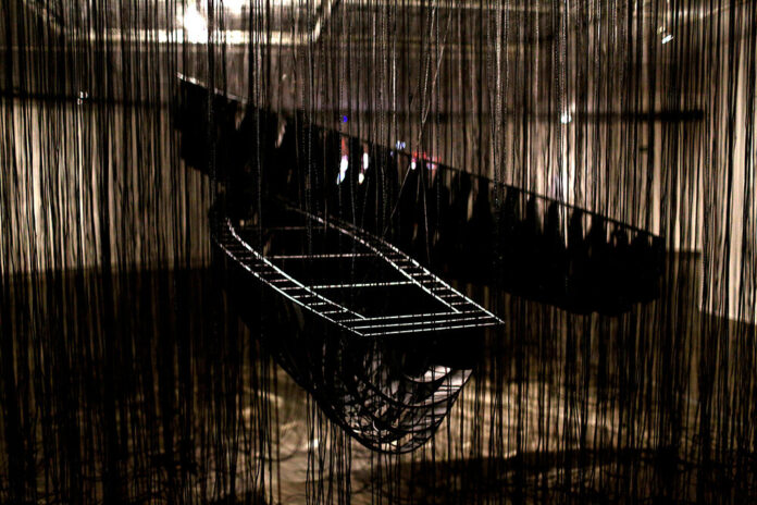 installation by the japanese artist Chiharu Shiota wirh two boats and many black ropes around them