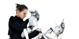 Photograph of the performer Marta Cuscunà sitting on the ground with her puppets