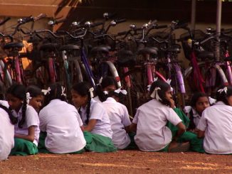 Nella foto: giovani ragazze sedute per terra di fronte a molte biciclette.