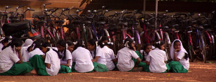 Nella foto: giovani ragazze sedute per terra di fronte a molte biciclette.