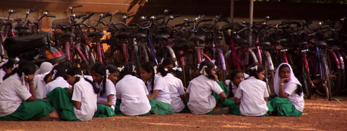 Pandemia e paesi poveri Nella foto: giovani ragazze sedute per terra di fronte a molte biciclette.