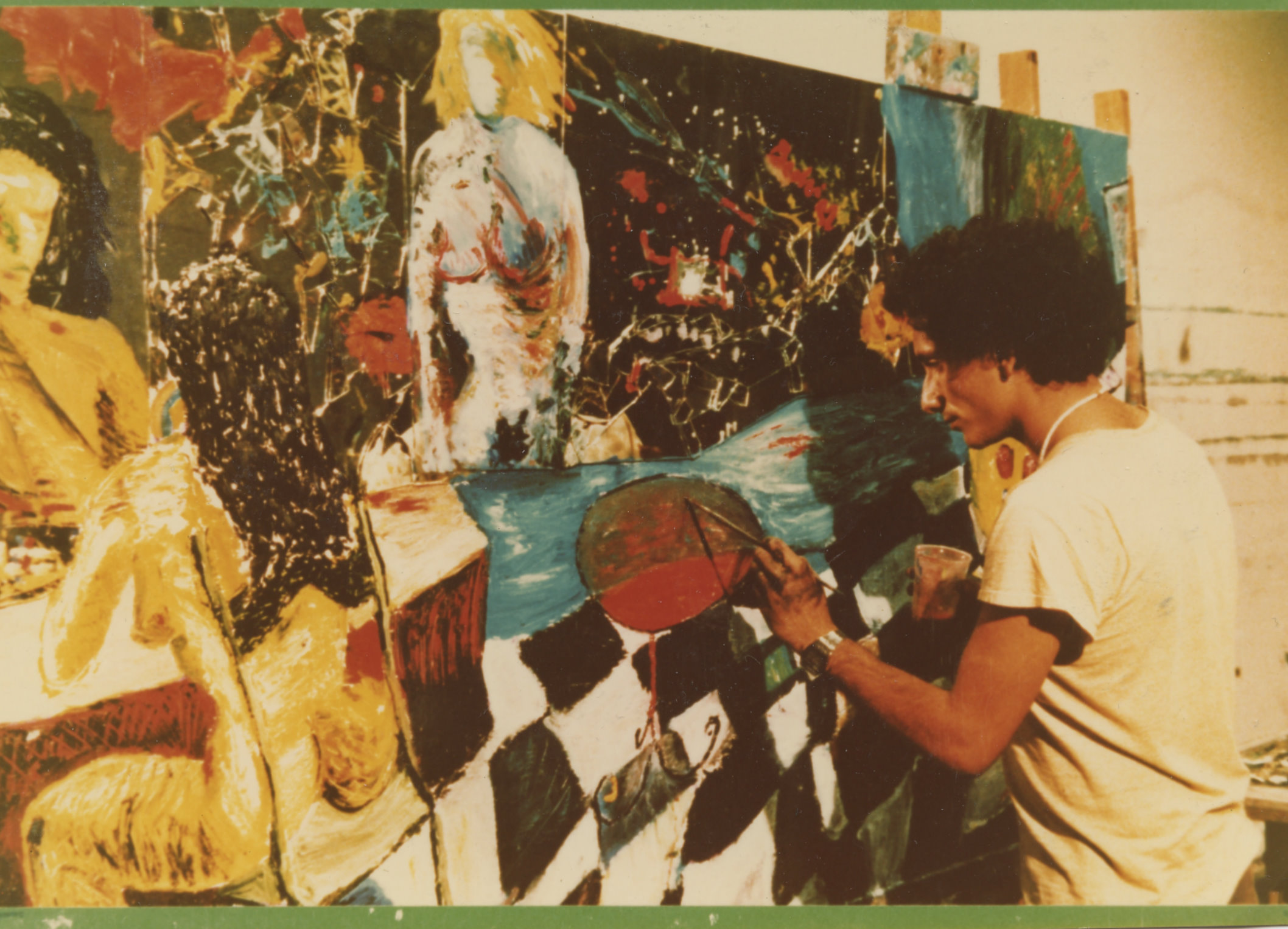 The picture shows Bedri Baykam painting a big canvas. The artist is on the right side of the picure, while the opposite side is covered by the big tableau he's working on