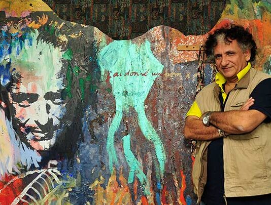 The picture shows artist Baykam in front of a murales he realkzed