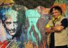 L'immagine mostra l'artista Baykam davanti ad un suo murales