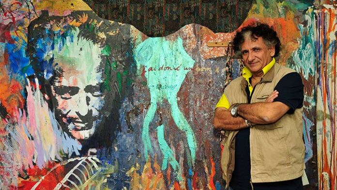 L'immagine mostra l'artista Baykam davanti ad un suo murales