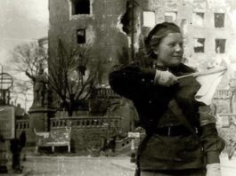in this black and white photo you can see on the right a young woman, an auxiliary of the Red Army; she puts in her hand a flag.