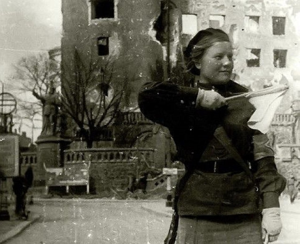 in this black and white photo you can see on the right a young woman, an auxiliary of the Red Army; she puts in her hand a flag.