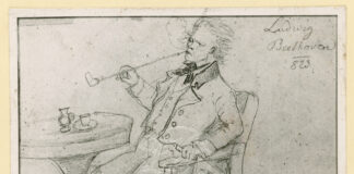 disegno in cui il grande compositore Beethoven è ritratto seduto a un caffè mentre fuma una lunga pipa, un giornale tenuto nella sua mani sinistra.