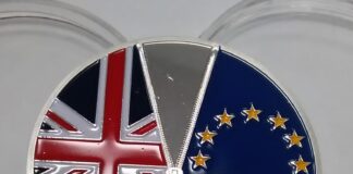 l'immagine mostra una medaglia metallica su cui sono incise le bandiere della union jack a sinistra e quela dell'Unione europea a destra, come se fossero du lati di una maglia, separata da una zip (anch'essa incisa)