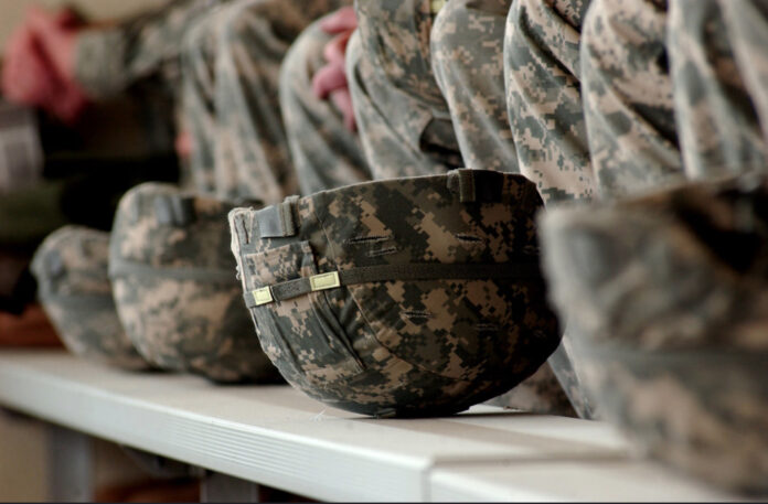 in the color photo you can see many soldiers' helmets lined up with the typical colors of the military style, and, behind them, the uniforms of the soldiers.