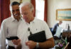 in the colored photo you can see two men, Barack Obama and Joe Biden. Biden wears glasses on the shirt and puts in his hands a tablet and a tape recorder.