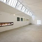nella foto a colori si vede la sala bianca di un museo a Biella con alcune opere attaccate alle pareti