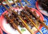 The picture shows a plate full of meat skewers on a white and blue tablecloth