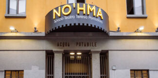 L'esterno dello Spazio Teatro No'hma di Milano dove campeggiano l'insegna, appena sotto la scritta Acqua Potabile e il cancello d'entrata -chuso- con tre locandine