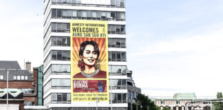 nella foto a colori si vede un edificio sul quale è stato affisso un poster di Amnesty International con l'immagine della leader Aung San Suu Kyi