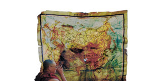 nella foto si vede una cartina geografica dell'Asia ammirata da un monaco tibetano di profilo, forse il Dalai Lama.