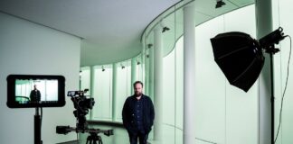 nella foto a colori si vede un signore in piedi vestito di scuro, il critico d'arte Nicolas Ballario, di fronte ad una telecamera al Museo delle Culture