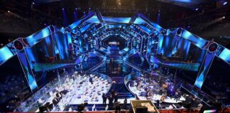 nella foto a colori si vede il palcoscenico del festival di Sanremo con luci blu e la postazione dell'orchestra ai lati dello stesso.