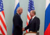 la foto a colori mostra in primo piano il Vicepresidente Usa Joe Biden che stringe la mano al Primo Ministro russo Vladimir Putin; sullo sfondo le bandiere dei due Paesi