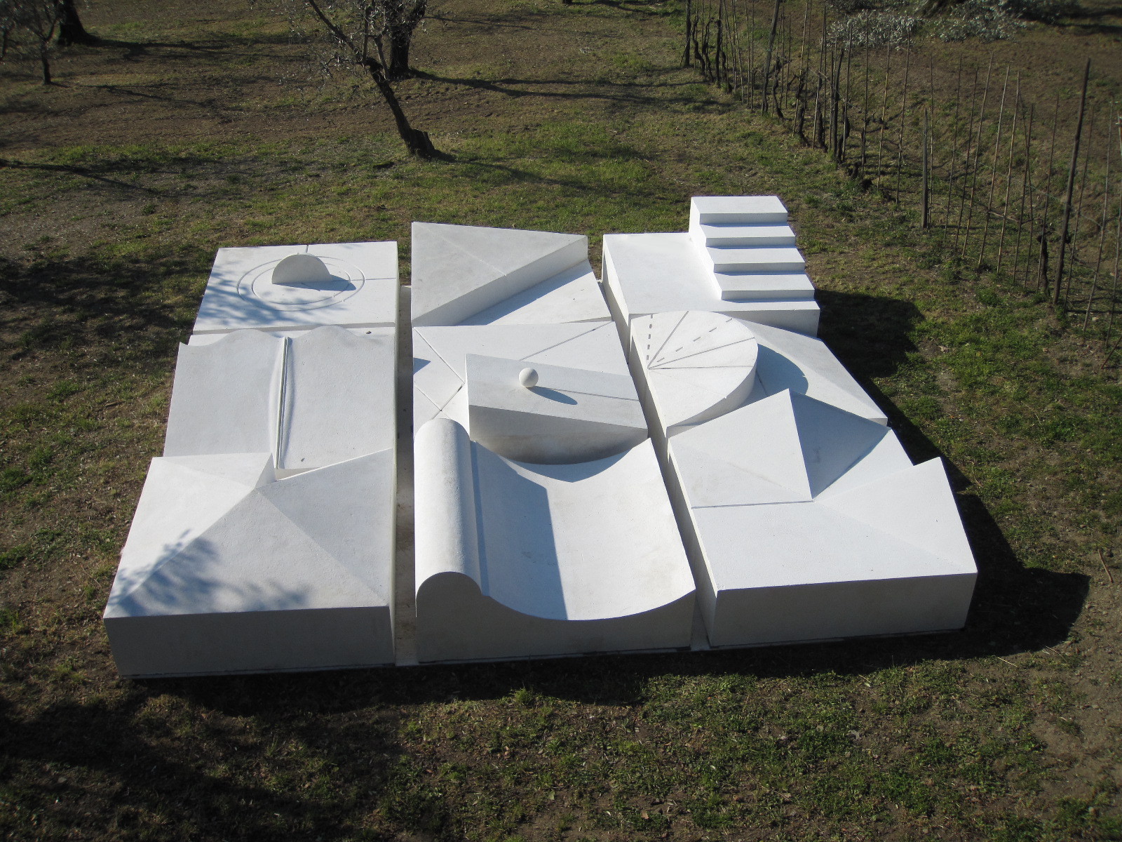 Fotografia di un'opera ambientale di Dani Karavan, una composizione di blocchi bianchi, di varie forme, poggiate su un terreno erboso.